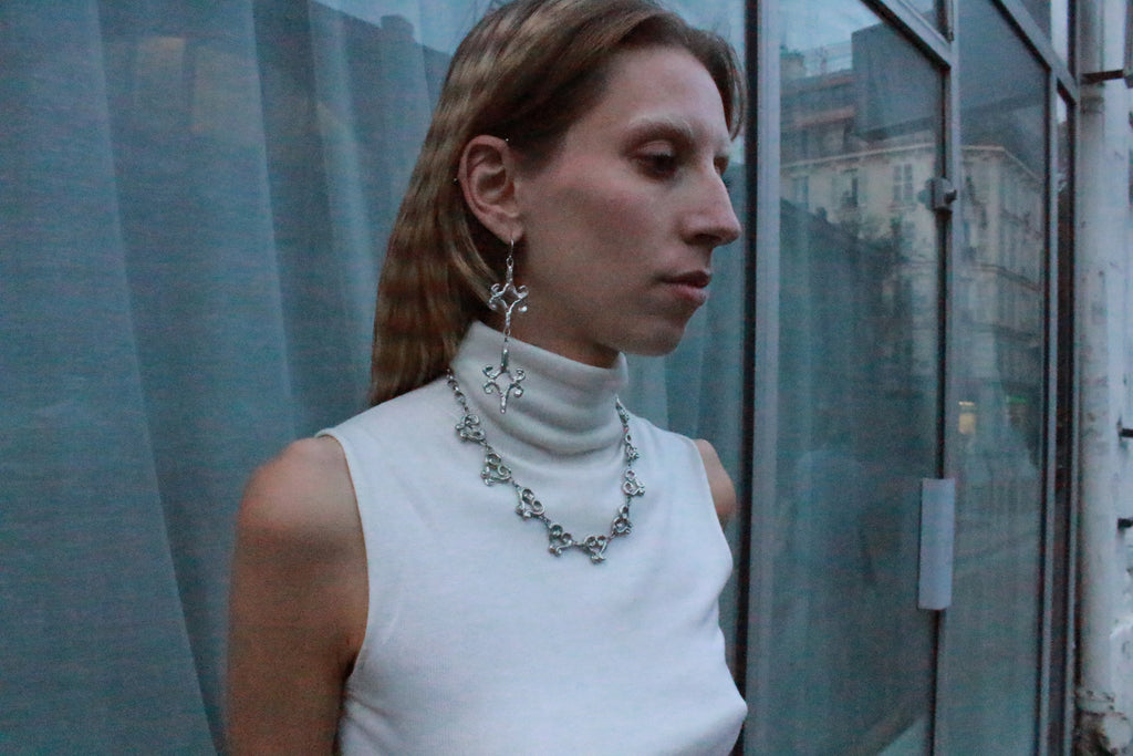 close up shooting éditorial boucles d'oreilles losange stylisé inspirées de la ferronnerie d'art avec pendentifs fondus individuellement selon un procédé artisanal unique mis au point par la marque de bijoux Lolie, finition argenté