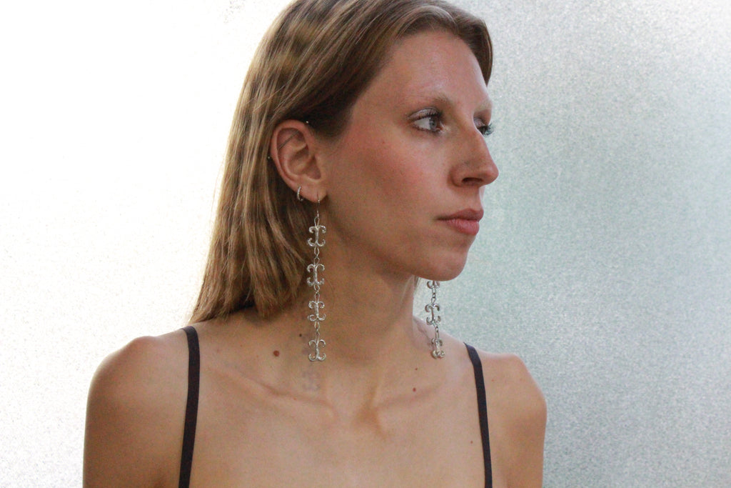 shooting éditorial boucles d'oreilles volutes inspirées de la ferronnerie d'art avec pendentifs fondus individuellement selon un procédé artisanal unique mis au point par la marque de bijoux Lolie, finition argenté