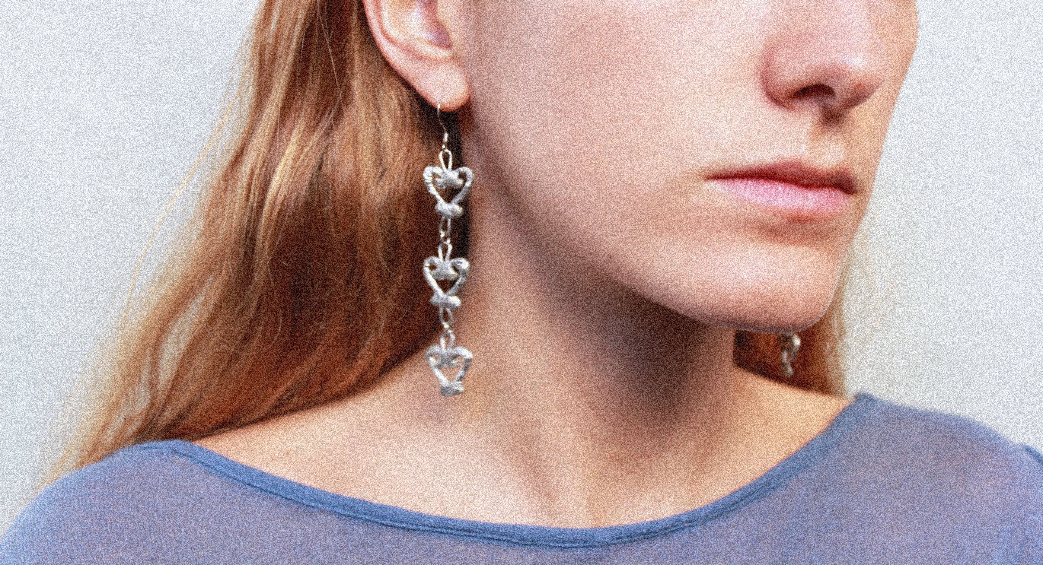 Close up boucles d'oreilles uniques triple coeur en étain fondu artisanalement à Paris