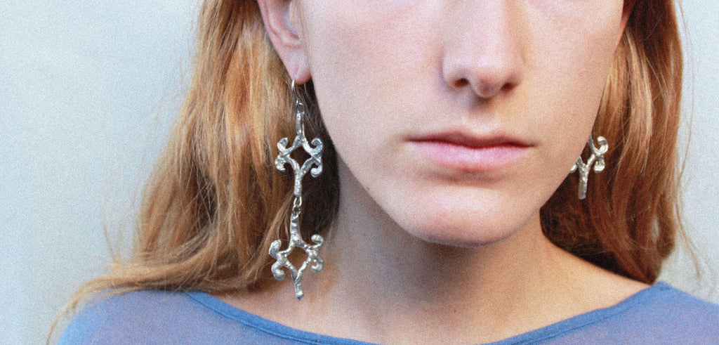 Close up boucles d'oreilles losange stylisé inspirées de la ferronnerie d'art avec pendentifs fondus individuellement selon un procédé artisanal unique mis au point par la marque de bijoux Lolie, finition argenté