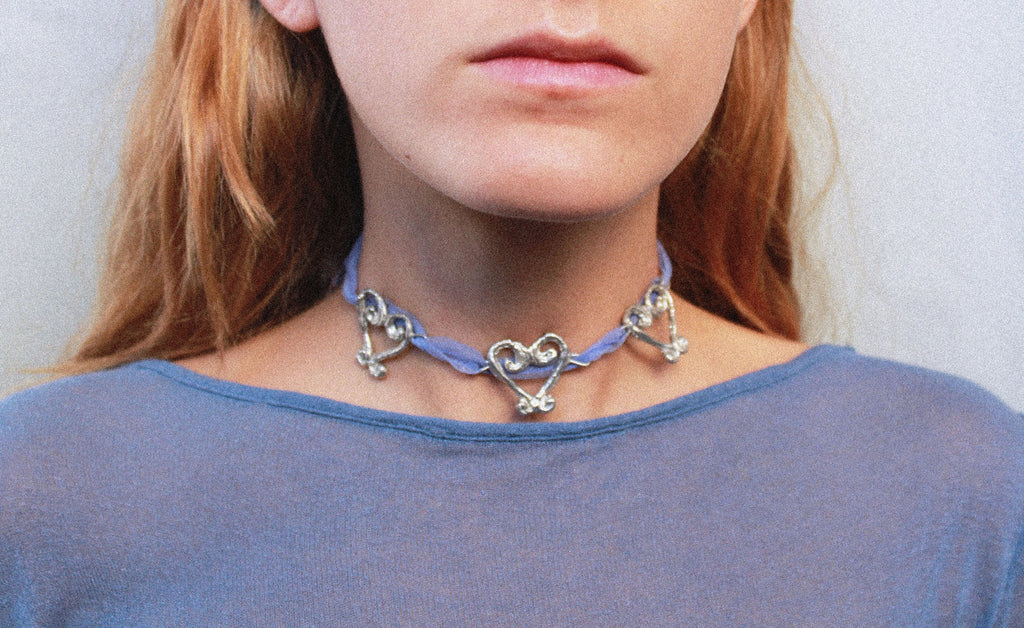 Close up collier organza et pendentifs coeurs fondus individuellement selon un procédé artisanal unique mis au point par la marque de bijoux Lolie, finition argenté, tissu organza lavande